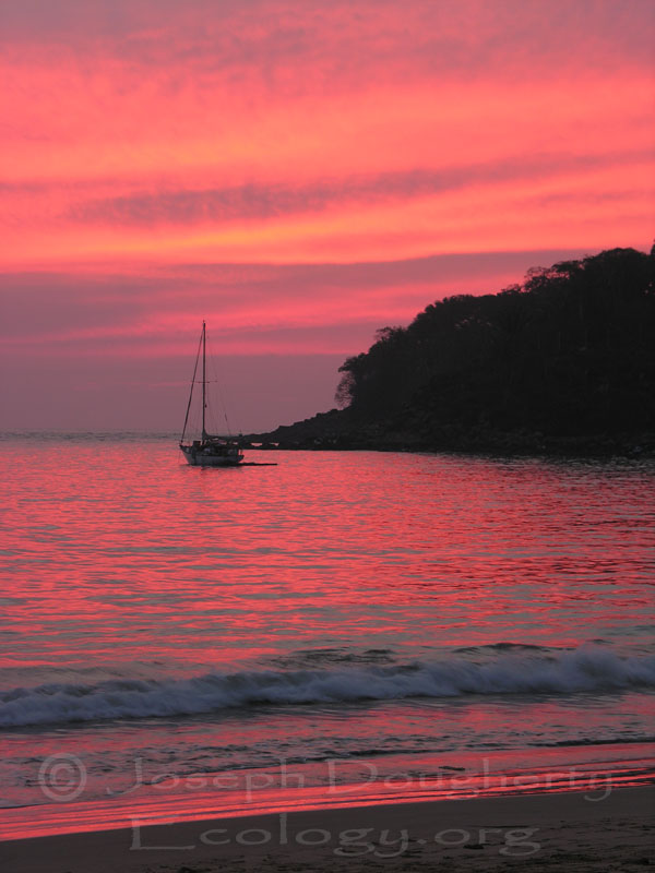 Pacific Ocean tropical sailboat afterglow of colorful sunset.