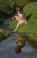 Young boy playing in grassy stream.