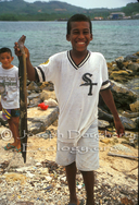 Honduran boy proudly displays the eel he caught by hand-lining in the shallows near French Harbor.