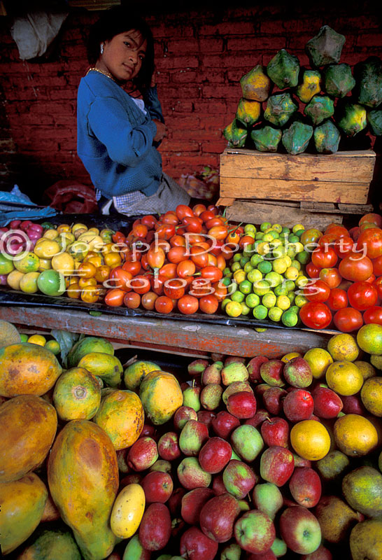 Produce market, indigenous girl selling tropical fruit, in Otovalo.